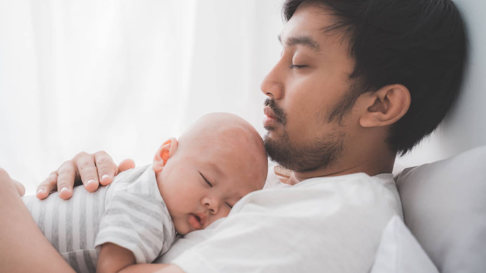 man sleeping with baby on chest