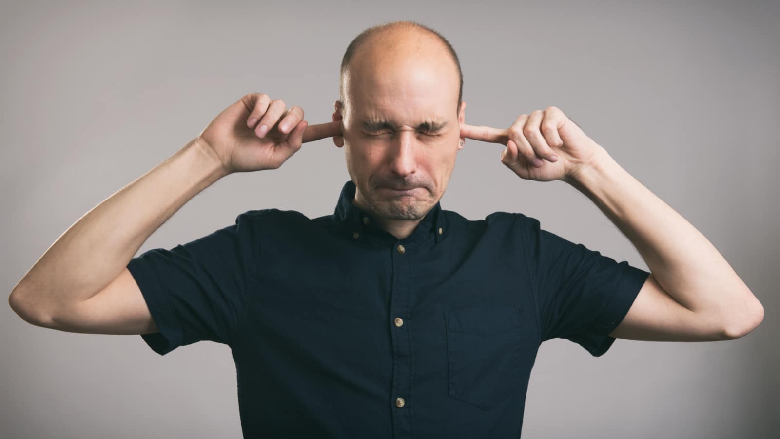 man with fingers in ears