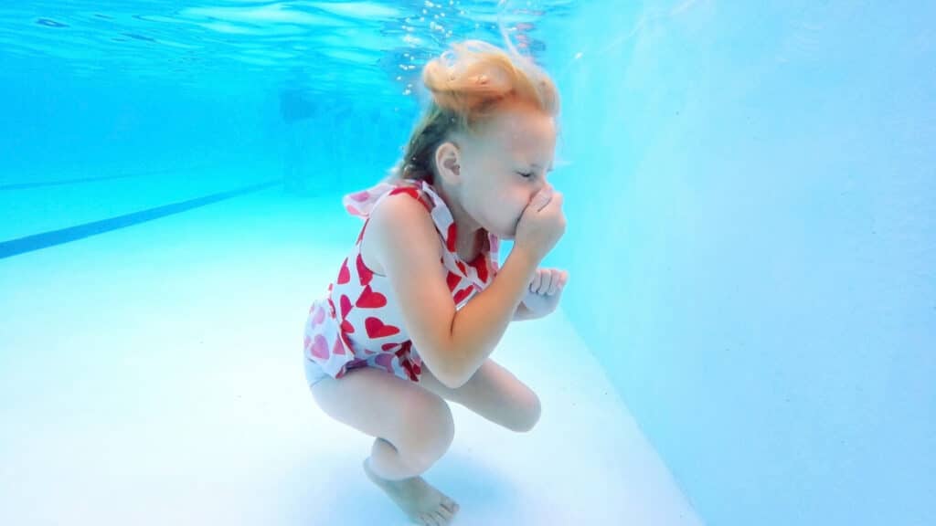 holding nose underwater pool