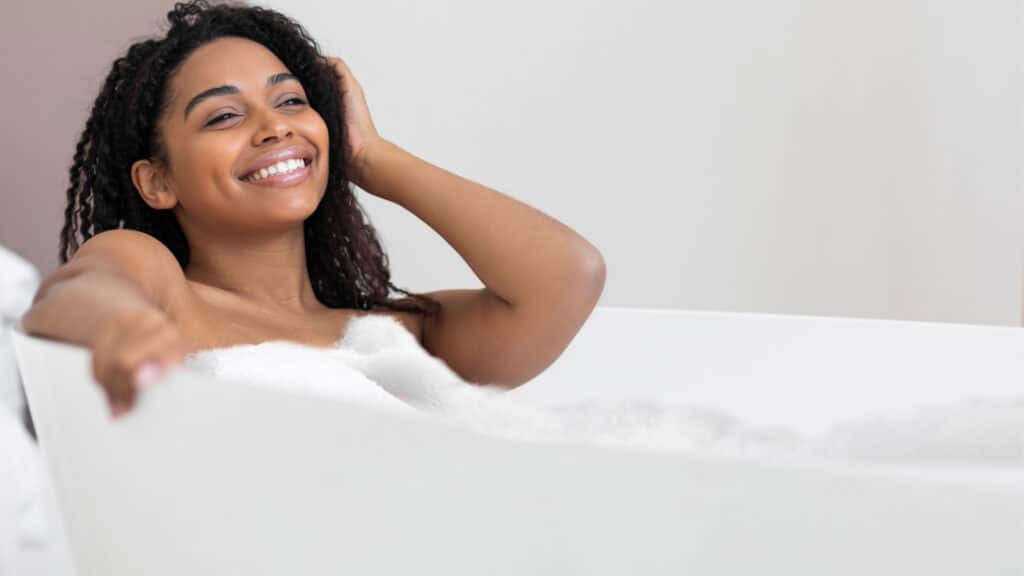 happy Black woman in bath tub bubbles