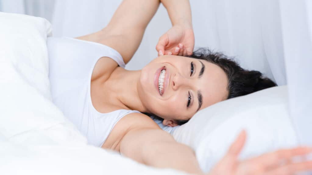 happy woman stretching in bed