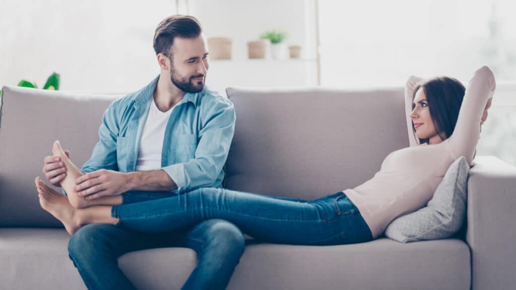 man giving woman foot rub on couch