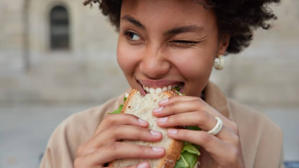 Black woman eating sandwich wink