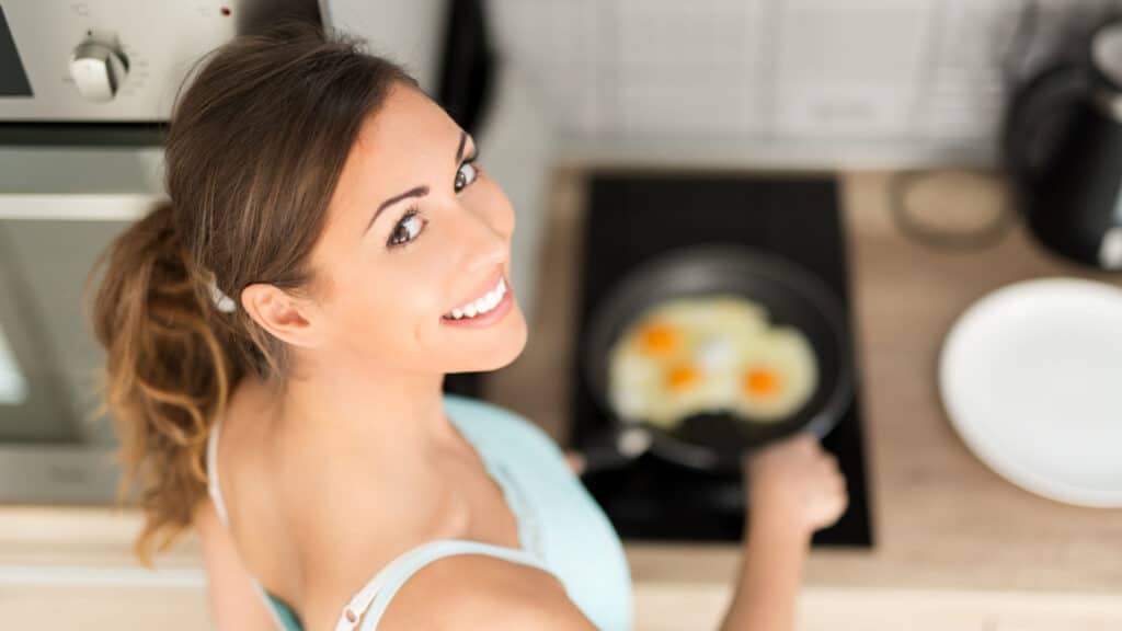 beautiful woman cooking eggs