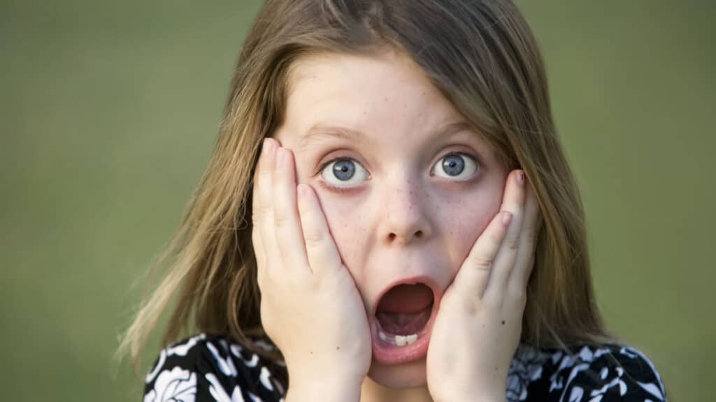 shocked kid open mouth hands over cheeks