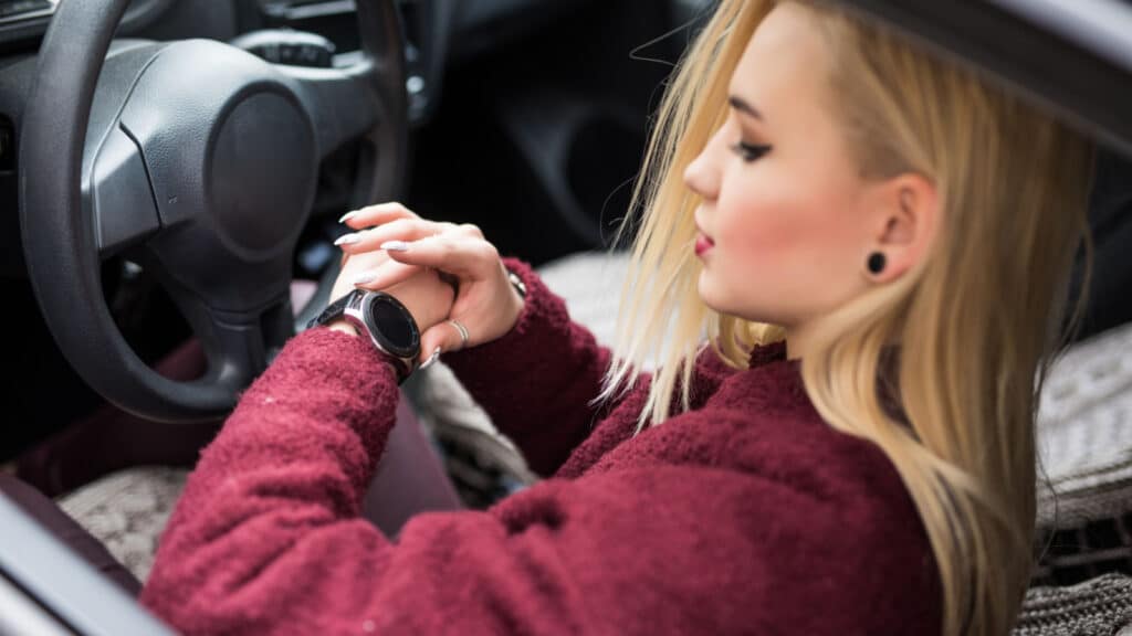 woman looking at time watch in care driving running late